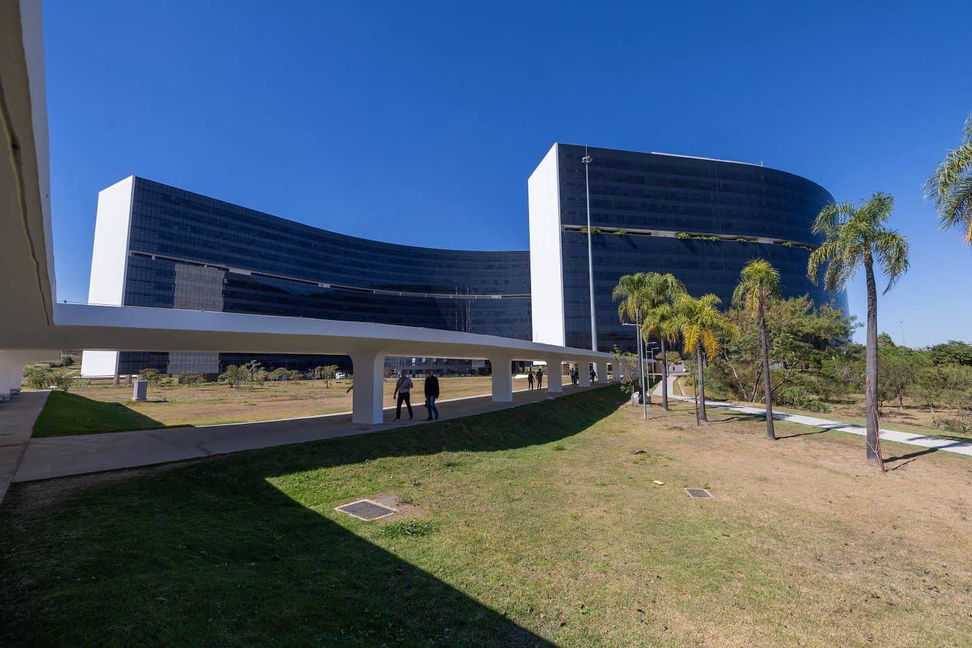 Edifícios modernos com fachada de vidro refletindo o céu azul.