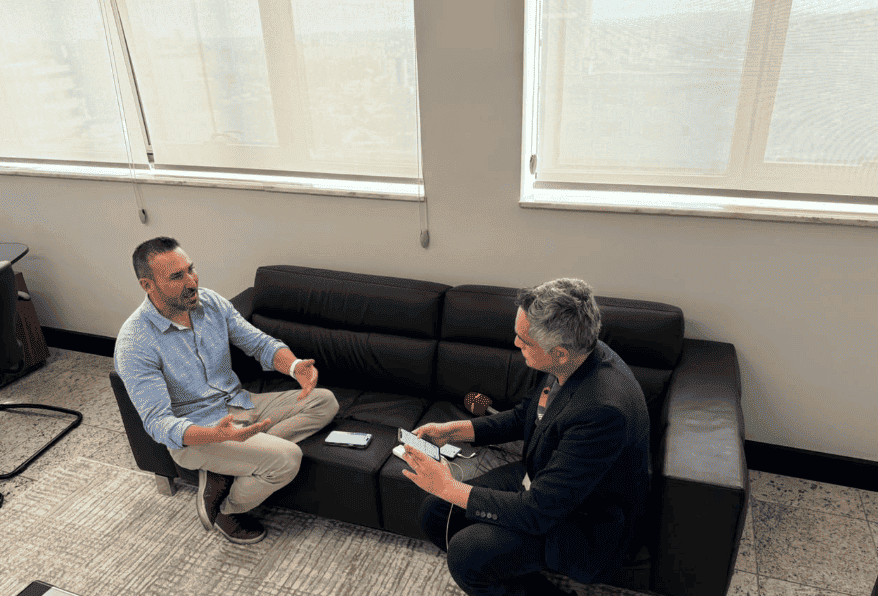Entrevista entre Fábio Moreira e jornalista na sala de reuniões.