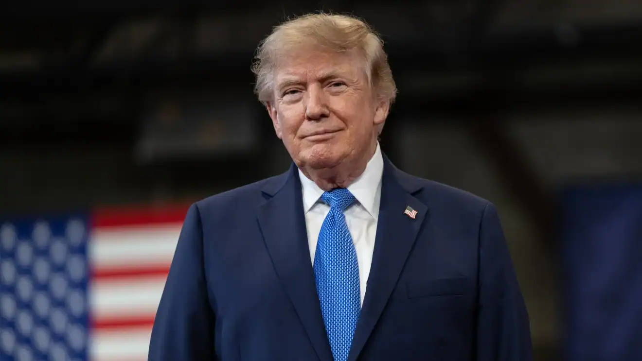Imagem de Donald Trump em evento público, usando terno azul e gravata azul.