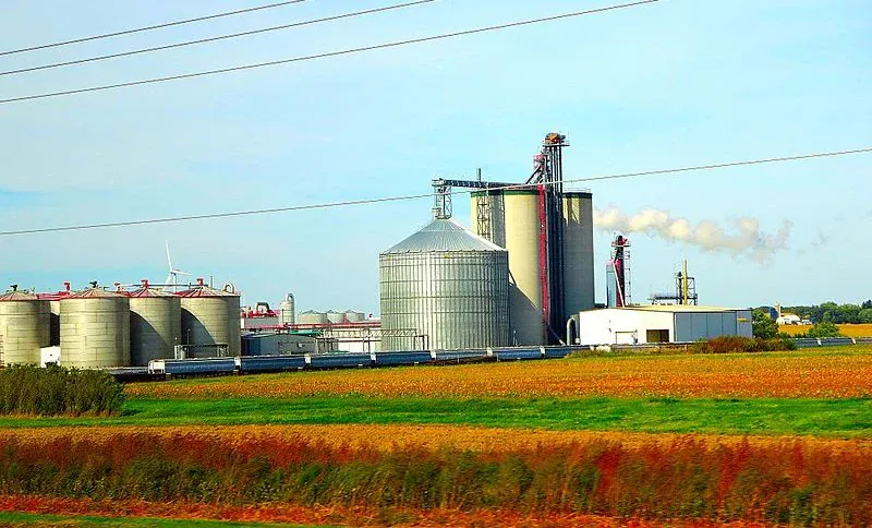 Instalação industrial com silos e estruturas de processamento em campo aberto.